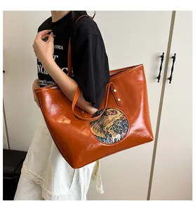 Detail of caramel tote bag with round ethnic elephant relief and waxy leather texture