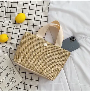 Macro view of woven straw tote bag with canvas handles and interior phone storage