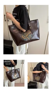 Close-up of embossed vintage totem pattern and polished leather on brown tote bag