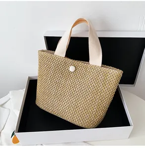 Detail of woven straw tote bag with round white buckle inside a white gift box