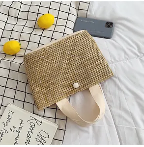 Detail of hand-woven straw tote bag with canvas handle and white button closure for summer