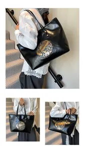 Detail shot of black glossy tote bag with ethnic pattern patches and gold rivets