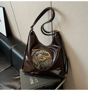 Detail of dark brown leather hobo bag with elephant metal relief on textured surface