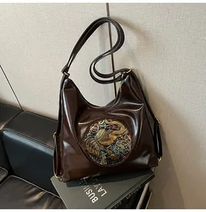 Close-up of vintage brown leather bag featuring an intricate round elephant relief pattern