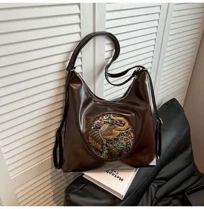 Detail of dark brown glossy hobo bag featuring a retro elephant relief and metal zipper