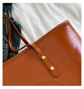 Detailed macro view of caramel leather tote bag stitching and golden metal rivets