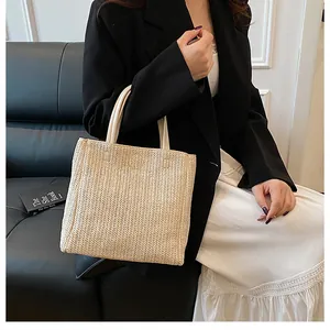 Detailansicht der beigen Strohtasche mit feiner Textur und doppelten Henkeln für Damen