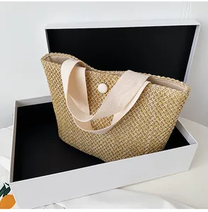 Close-up of the fine straw weave texture and canvas handles on a summer tote bag
