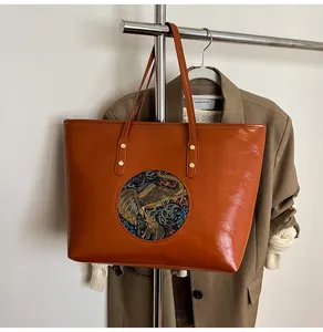 Detail of vintage brown tote bag featuring a round elephant totem embossed decoration