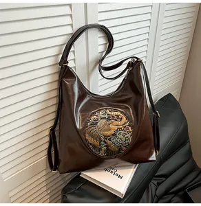 Detail of dark brown leather backpack with vintage elephant embossed metal ornament