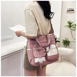 Detail of pink and white nylon crossbody bag featuring multi-pocket design and strap