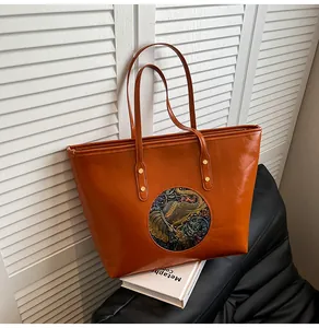 Detail of retro brown leather tote with ethnic elephant relief and gold rivets