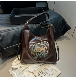 Close-up of vintage brown leather bag featuring an embossed elephant medallion with colorful enamel