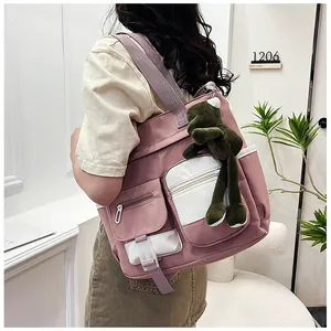 Detail view of large canvas crossbody bag in purple and beige with green frog charm