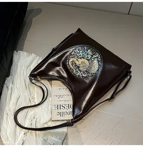 Detailed macro shot of dark brown glossy leather tote featuring an elephant relief carving