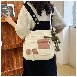 Detail of multi-pocket canvas crossbody bag with cream and pink panels and frog plush