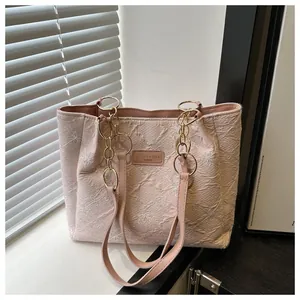 Detail of light pink tote bag featuring quilted flower pattern and gold chain straps