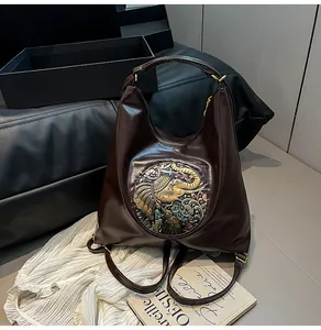 Detail of dark brown leather tote featuring an ornate elephant relief and metal emblem