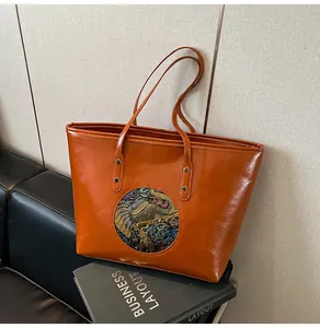 Close-up of vintage brown leather tote bag featuring an embossed elephant medallion detail