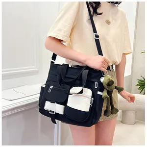 Detail view of large canvas tote bag with multiple zip pockets and green frog pendant