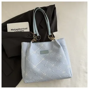 Close-up of light blue quilted tote bag with floral embroidery and gold hardware