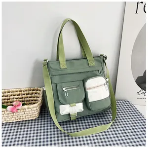 Detail of green canvas tote bag with contrast pockets and adjustable shoulder strap