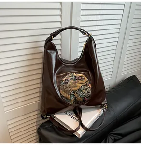 Detail of dark brown glossy tote bag with vintage elephant emblem on white books