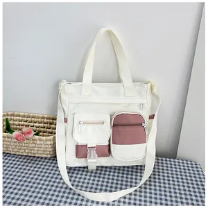 Detail of pink and white canvas tote bag with functional pockets and shoulder straps