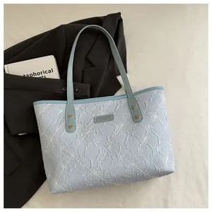 Detail of light blue pleated tote bag featuring white floral embroidery and metal logo