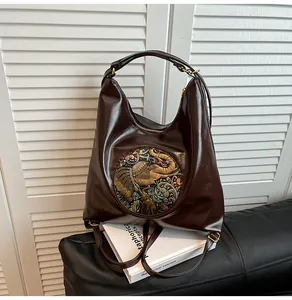 Detail of dark brown glossy leather bag featuring a colorful relief elephant emblem