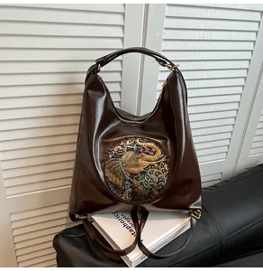 Close-up of deep brown glossy leather bag featuring retro elephant relief and floral patterns