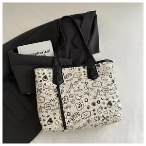 Close-up of contrast woven tote bag featuring black doodle print and leather trim