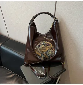 Detail of dark brown leather bag with elephant metal relief and adjustable straps