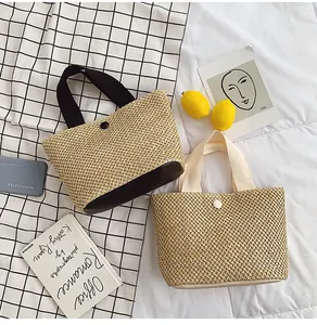Close-up of woven straw handbag texture with contrast handles and button closure detail