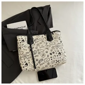 Detail of woven tote bag with cartoon graffiti and black leather handles shown with props