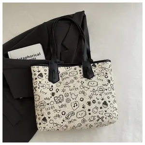Detail of woven tote bag with graffiti print and black leather handles on a blazer