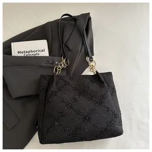 Close-up of black tote bag showing diamond texture and gold chain shoulder strap