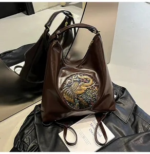 Detailed view of the dark brown PU leather bag with embossed elephant metal motif