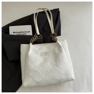 Detailed close-up of a white quilted tote bag with golden chain handle and a leather logo