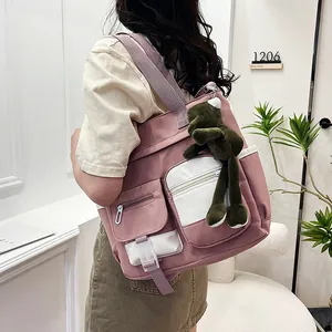 Pink and white canvas backpack with multi-pocket design and green frog plush pendant