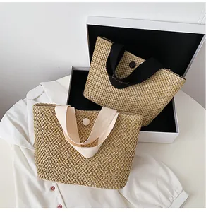 Detail of hand-woven straw tote bags with button closure and fabric handles in two colors