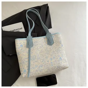 Flat lay of woven tote bag with blue floral pattern, faux leather straps and accessories