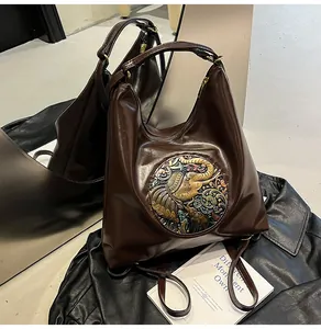 Detail of dark brown leather tote featuring vintage bronze elephant relief and zipper