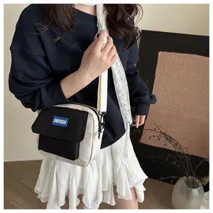 Détail d'un sac bandoulière bicolore avec logo FANYISSA et bandoulière tissée