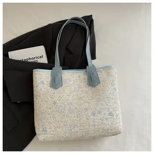 Macro detail of woven tote bag with light blue leather straps and floral texture