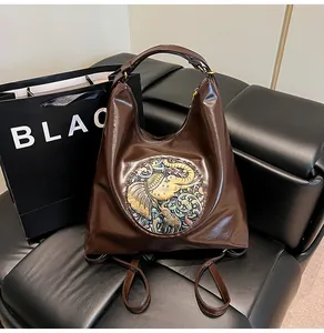 Detailed close-up of dark brown leather backpack featuring ethnic elephant patch embroidery