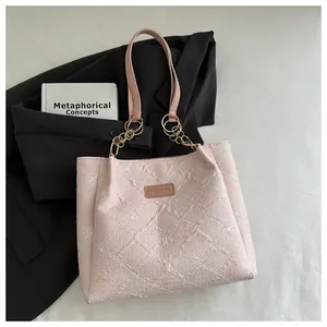 Close-up of pink quilted tote bag with floral embroidery and gold metal chain strap