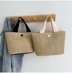 Detail of handwoven straw tote bags with circular buckles and canvas handles on a wall