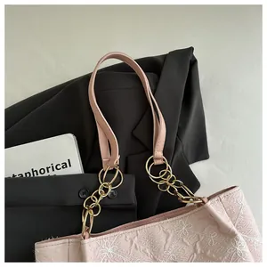 Close-up of pink tote bag with white floral embroidery and gold metal chain strap