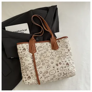 Macro shot of large canvas tote bag with brown cartoon prints and leather handles